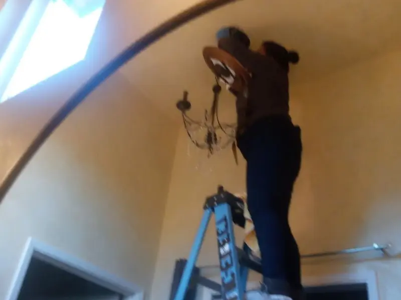 Electrician installing a chandelier in a Sikeston residence